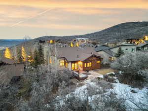 Snow covered back of property with a mountain view and a patio