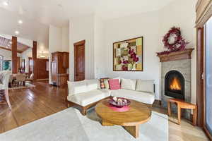 Living room featuring wood-type flooring, a fireplace, vaulted ceiling, and recessed lighting