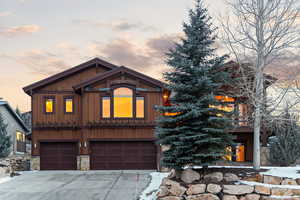 Chalet / cabin featuring a garage, stone siding, driveway, and board and batten siding