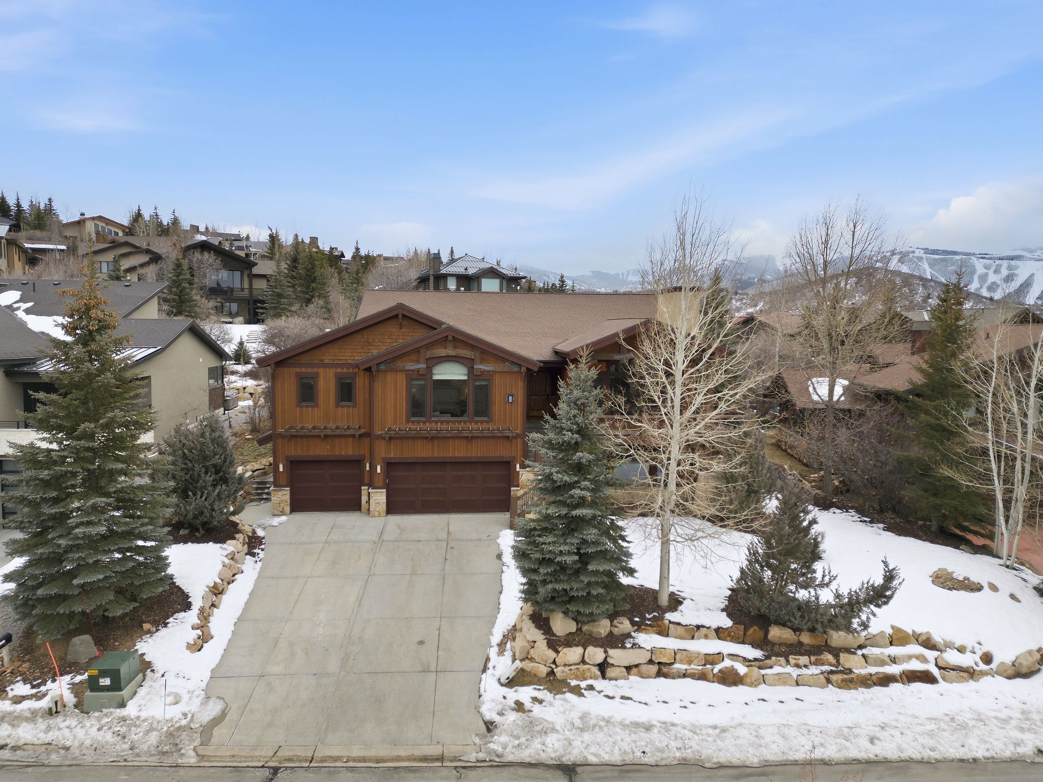 Chalet / cabin featuring a garage, driveway, and stone siding