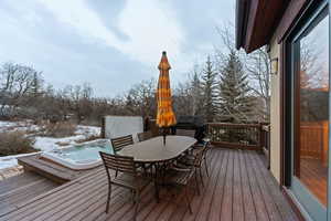 Snow covered deck featuring outdoor dining area and a grill
