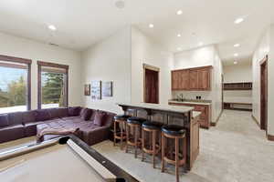 Living room featuring bar with sink, light stone finish flooring, recessed lighting, and billiards table