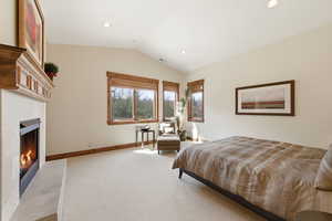 Bedroom featuring a tiled fireplace, light colored carpet, and recessed lighting