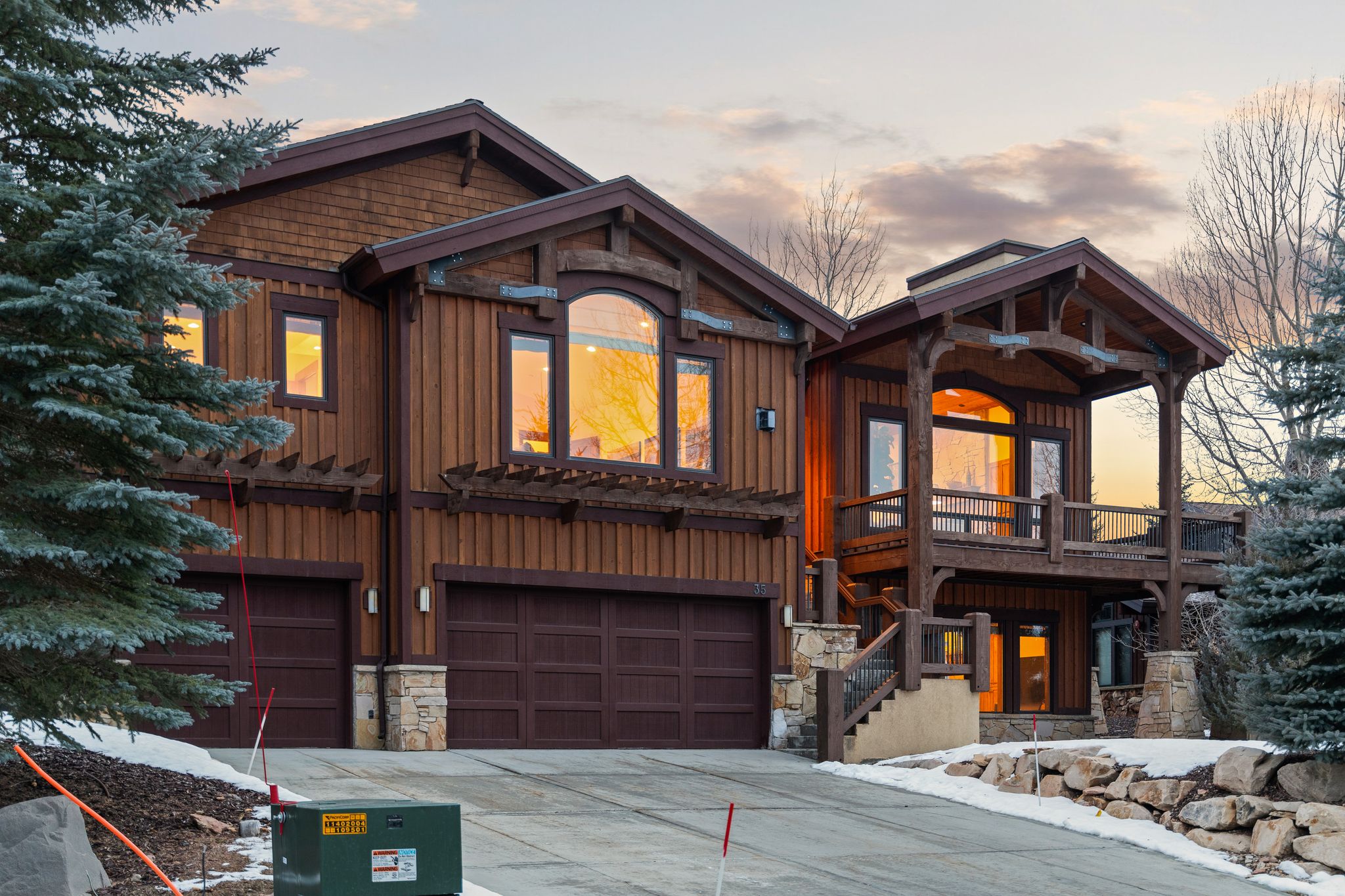 Chalet / cabin with board and batten siding, a garage, stone siding, and concrete driveway