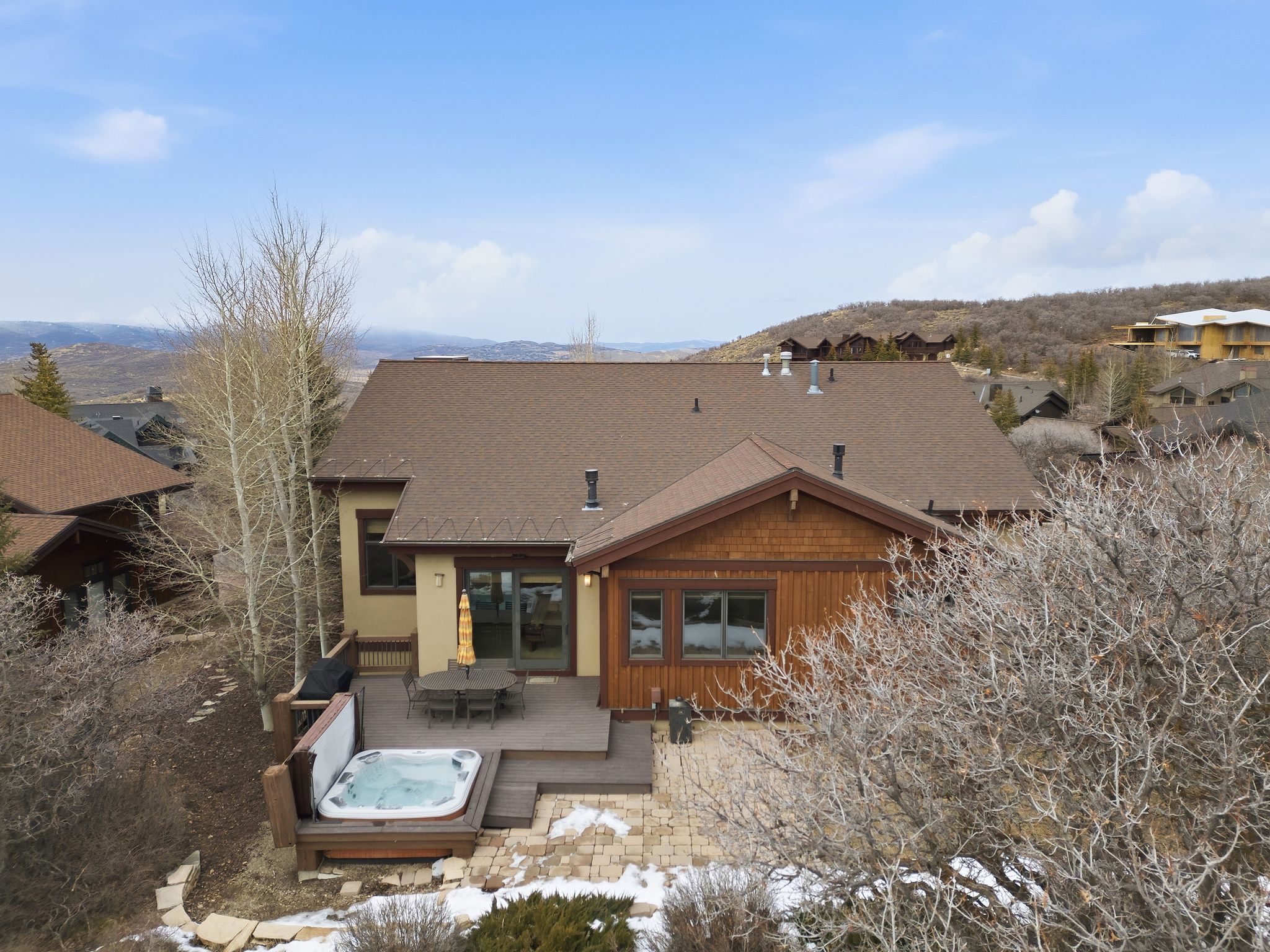 Rear view of property with a hot tub, outdoor dining space, and roof with shingles