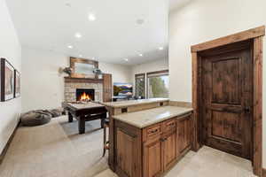 Kitchen featuring a kitchen bar, a stone fireplace, a peninsula, open floor plan, and recessed lighting