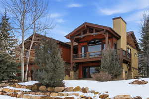 View of front facade with a chimney and stone siding