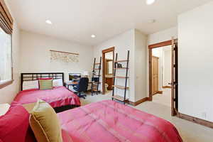 Bedroom with light colored carpet, recessed lighting, an office area, and ensuite bathroom