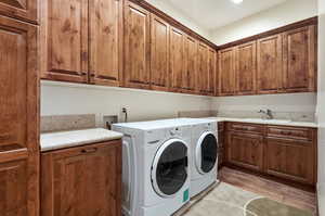 Laundry room featuring cabinet space, washing machine and dryer, and light wood-style flooring