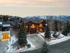 View of front of property with stone siding, a balcony, an attached garage, a mountain view, and a chimney