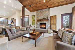 Living area with a vaulted wood ceiling, a stone fireplace, recessed lighting, and carpet