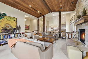 Living area featuring a fireplace, carpet, and a high wood beamed ceiling