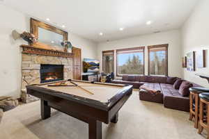 Game room with billiards table, light carpet, a stone fireplace, and recessed lighting