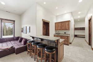 Kitchen with a breakfast bar, stone tile flooring, wood finish cabinetry, a peninsula, and recessed lighting