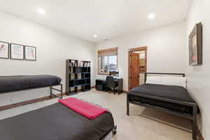 Carpeted bedroom with an office area and recessed lighting