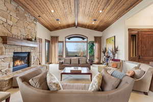 Carpeted living room with a fireplace, recessed lighting, and a high wood beamed ceiling