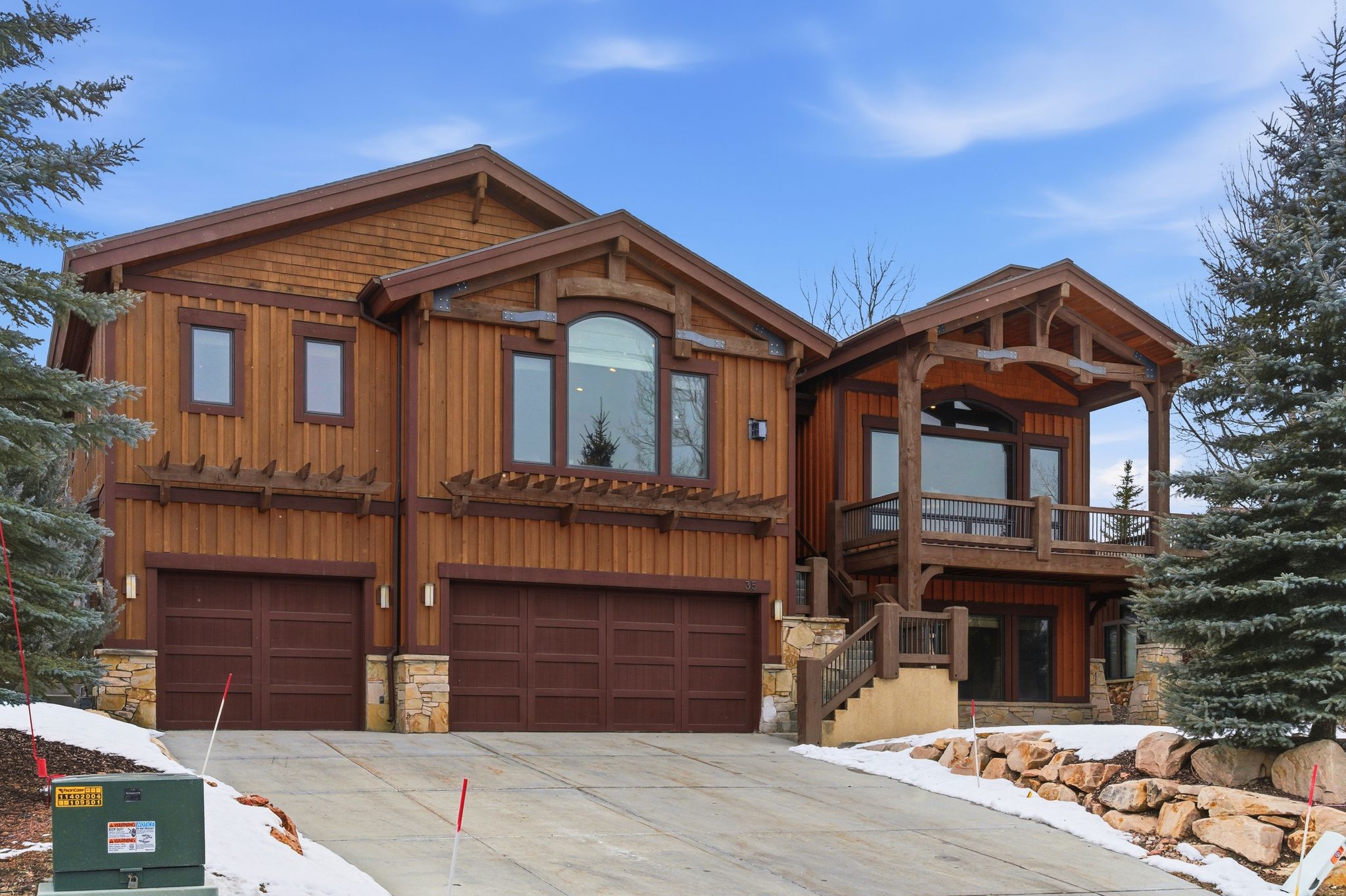 Chalet / cabin featuring stone siding, a garage, concrete driveway, and board and batten siding
