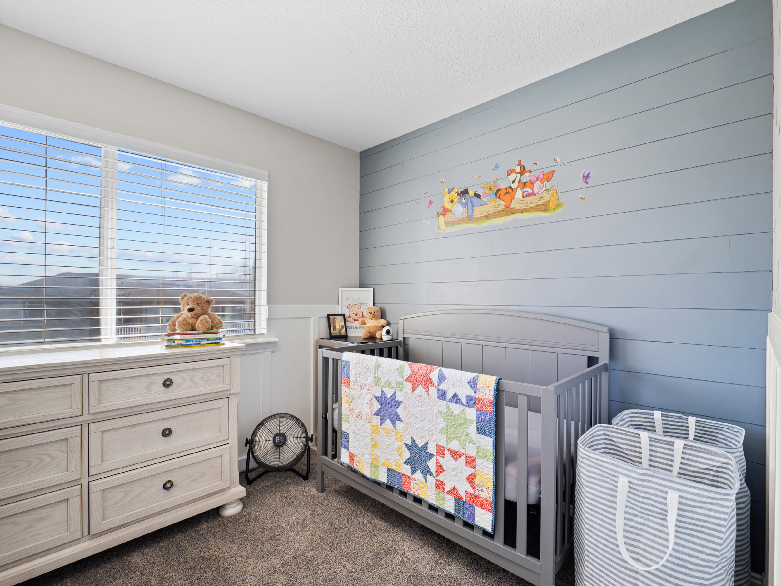 Bedroom with dark carpet, a nursery area, and wooden walls