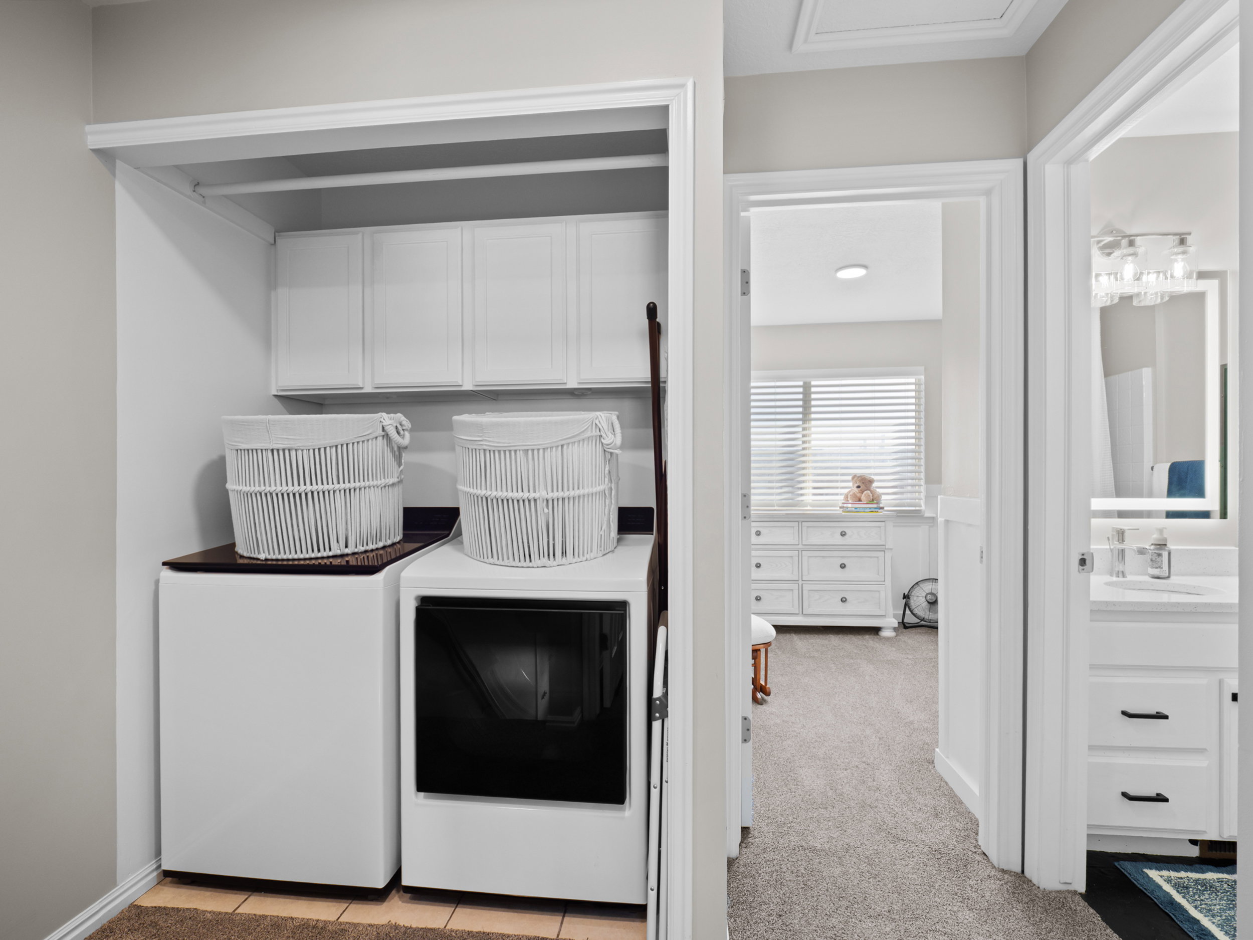 Laundry area featuring light colored carpet, cabinet space, and washing machine and clothes dryer
