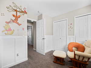 Sitting room featuring a wainscoted wall, a decorative wall, and dark carpet