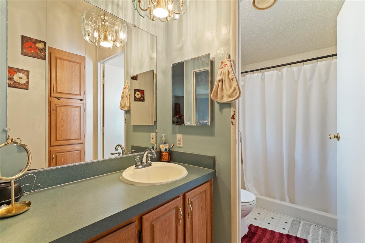 Full bathroom featuring vanity, a shower with shower curtain, hanging lights, and a textured ceiling