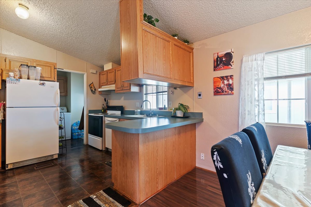 Kitchen with white appliances, a peninsula, washer / clothes dryer, and a textured wall