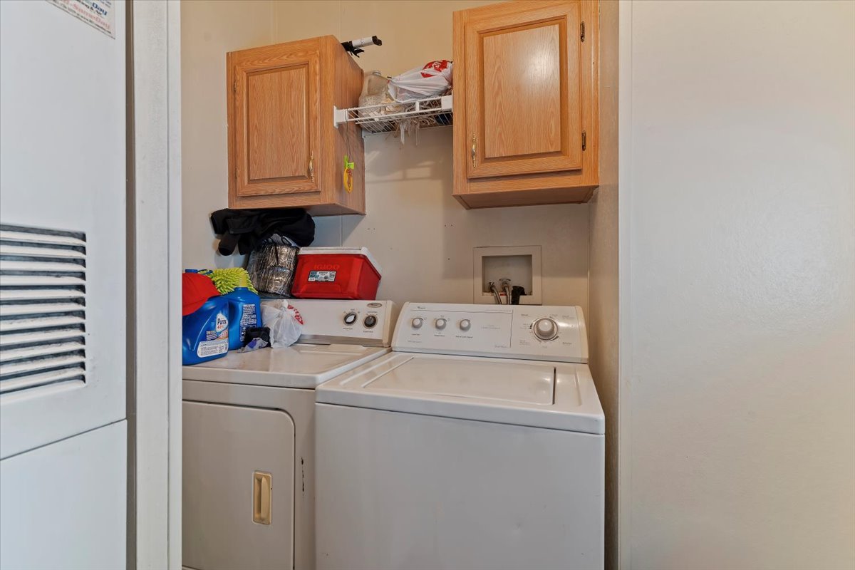 Laundry room featuring a heating unit, independent washer and dryer, and cabinet space