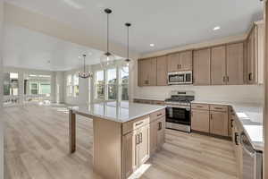 Kitchen with stainless steel appliances, open floor plan, light wood-style flooring, a center island, and a breakfast bar