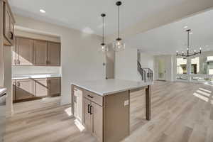 Kitchen featuring light wood-style flooring, open floor plan, light countertops, a kitchen island, and stainless steel dishwasher