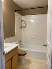 Full bathroom with vanity, wainscoting, a textured ceiling, and shower / washtub combination