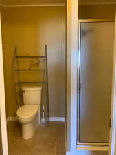 Full bathroom featuring a shower stall, light tile patterned floors, and ornamental molding