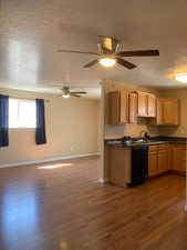 Kitchen with dark countertops, open floor plan, dishwasher, a textured ceiling, and dark wood finished floors