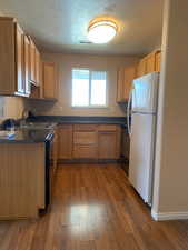 Kitchen featuring freestanding refrigerator, light wood finished floors, stainless steel range oven, a textured ceiling, and dishwasher