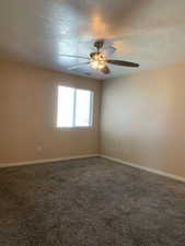 Carpeted empty room featuring a textured ceiling and a ceiling fan
