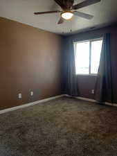 Spare room featuring a ceiling fan, dark colored carpet, and a textured ceiling