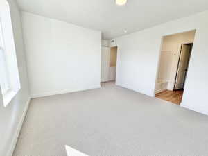 Unfurnished bedroom with light colored carpet and connected bathroom