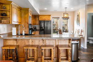 Kitchen featuring wood finish cabinetry, black appliances, open shelves, a kitchen breakfast bar, and a peninsula