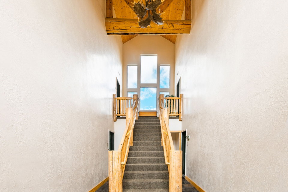 Staircase with a textured wall and beamed ceiling