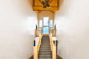 Staircase with a textured wall and beamed ceiling