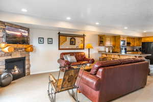 Living area featuring light carpet, recessed lighting, and a fireplace