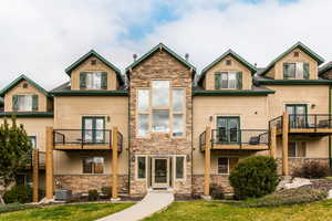 Rear view of property featuring french doors, stone siding, and a yard