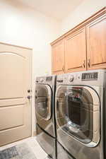 Laundry room featuring cabinet space, light tile patterned floors, and separate washer and dryer