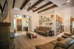 Living room featuring arched walkways, a ceiling fan, recessed lighting, and beam ceiling