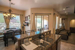 Kitchen with arched walkways, dark stone countertops, a textured ceiling, hanging lights, and light tile patterned floors