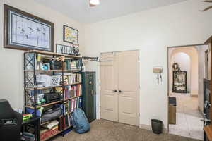 Office area featuring arched walkways, light carpet, and a ceiling fan