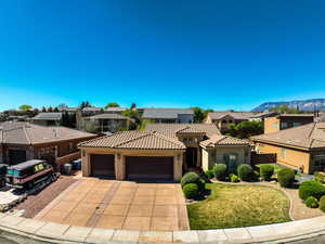 Mediterranean / spanish house featuring a residential view, a garage, stucco siding, driveway, and a tile roof