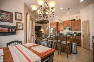 Dining room with a textured ceiling, a chandelier, a tile fireplace, arched walkways, and light tile patterned floors