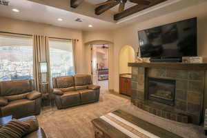 Living area featuring ceiling fan, arched walkways, light colored carpet, a glass covered fireplace, and recessed lighting