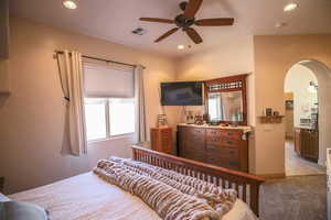 Carpeted bedroom with arched walkways, multiple windows, recessed lighting, and a ceiling fan