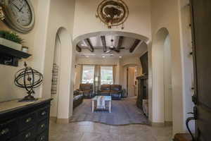 Living room featuring a ceiling fan, arched walkways, and beamed ceiling